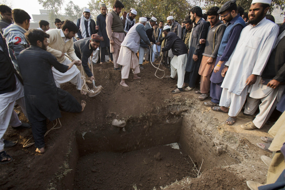 Pakistani villagers bury a body of the principal of the Army Public School that was attacked the day before by Taliban gunmen in Peshawar, Pakistan, Wednesday.