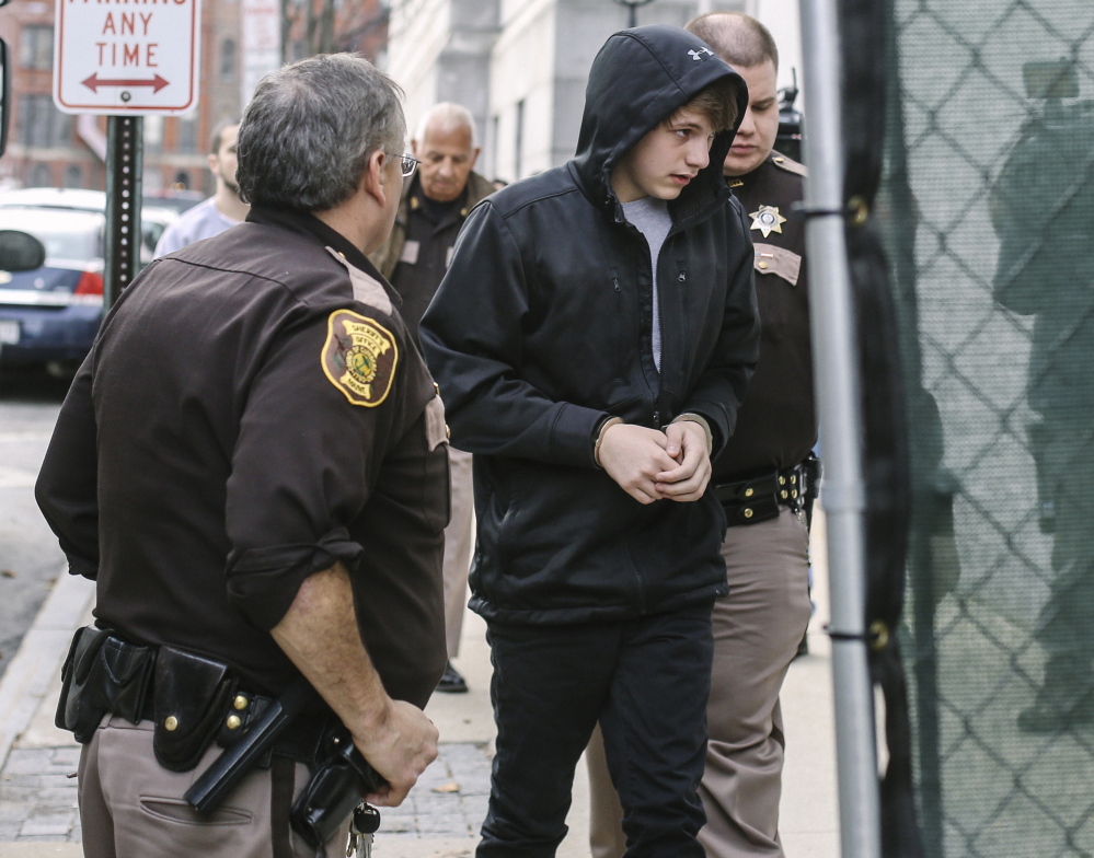 Sixteen-year-old Justin Woodbury is escorted into the Cumberland County Courthouse in Portland for his initial appearance in juvenile court Thursday. Woodbury is accused of sending threatening emails to Windham school administrators, leading to a three-day shutdown in Regional School Unit 14. The boy’s mother, Tina Woodbury, said her son “made a bad choice, but he’s not the monster they’re making him out to be.”