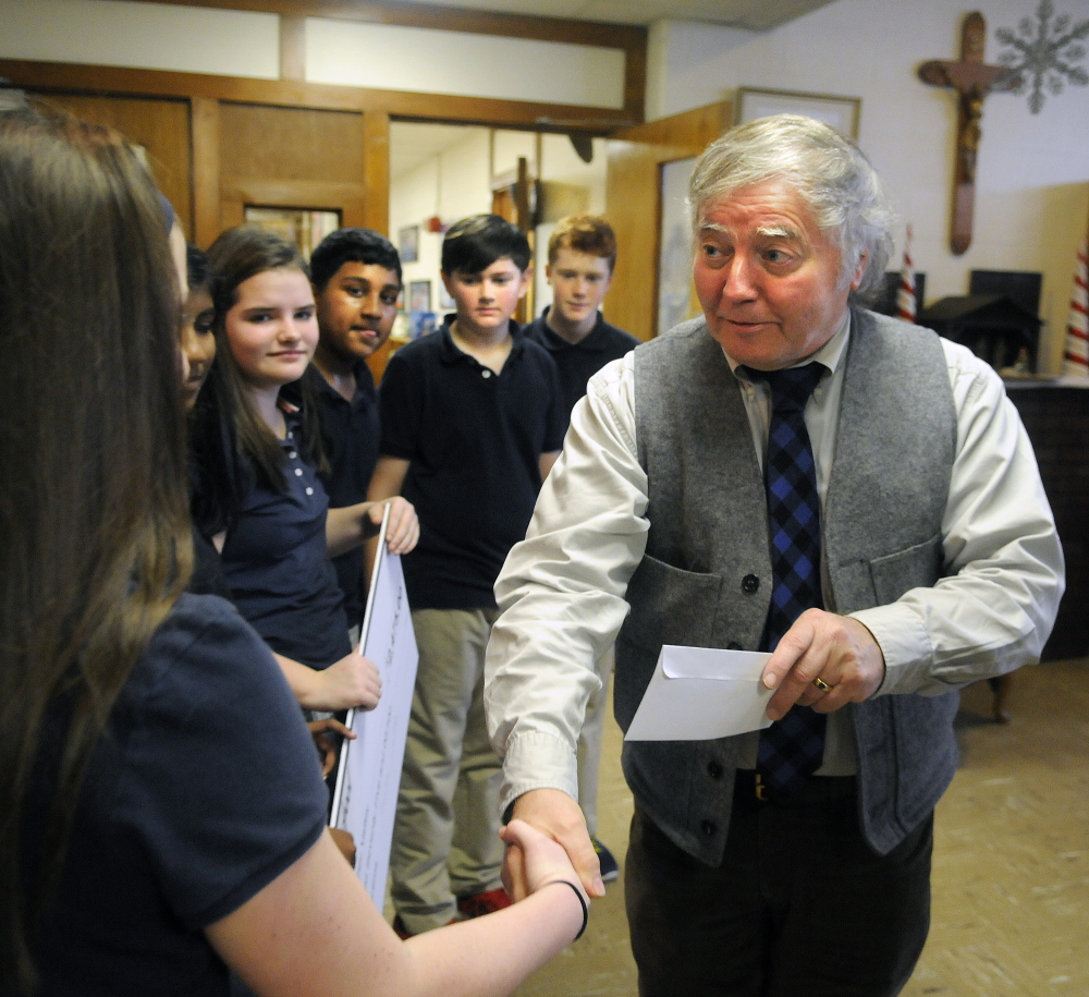 Rob Gordon, executive director of the United Way of Kennebec Valley, shakes hands Thursday with St. Michael School seventh-graders who helped raise the money at the school in Augusta for victims of two recent fires in the city.