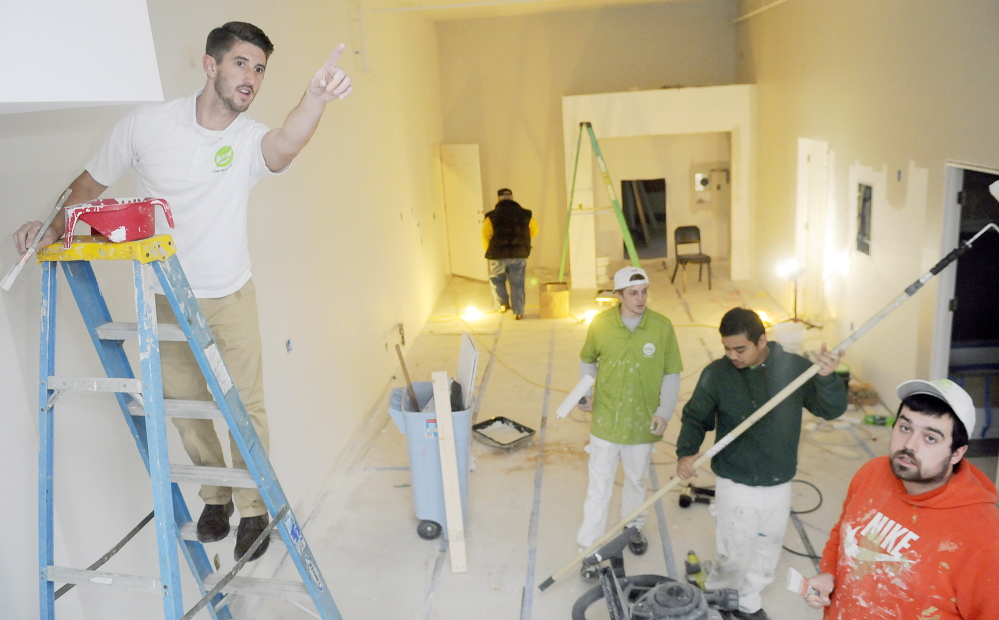 Ryan Guerrette, left, oversees a crew of painters on Thursday while painting Augusta apartments that belong to his family. Guerrette and his father, William, have opened a Wow 1 Day Painting franchise.