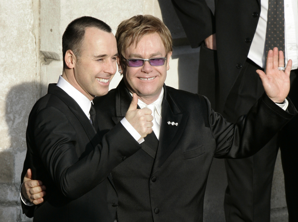 A December 2005 photo shows pop star Elton John, right, and his longtime partner David Furnish, embracing as they wave to members of the media and the public after they had a civil ceremony at the Guildhall in Windsor, England. John and Furnish officially married on Sunday.