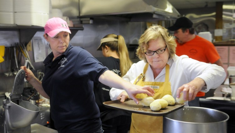 Kara Waller, left, collects potatoes to shred that her mother, Susan Kinsley, peeled and washed Sunday at Dennis’ Pizza in Gardiner for a latke party at the restaurant. Waller owns the establishment with her husband, Andy.