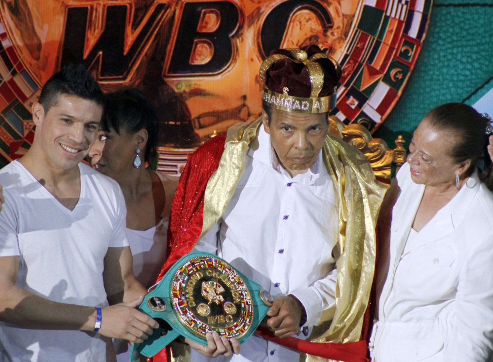 In this Monday, Dec. 3, 2012, file photo, the former heavyweight boxing champion Muhammad Ali, center, is crowned “King of Boxing” while accompanied by his wife, Lonnie, right, and Argentine boxer Sergio Martinez during the 50th convention of the World Boxing Council in Cancun, Mexico.