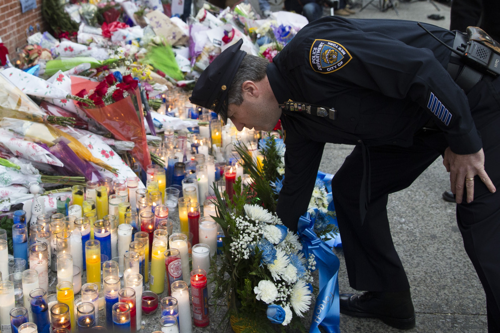 Patrick Lynch, president of the Patrolman’s Benevolent Association, places flowers at a makeshift memorial on Monday near the site in Brooklyn where New York police officers Rafael Ramos and Wenjian Liu were murdered Saturday. Police say Ismaaiyl Brinsley ambushed the officers in their patrol car in broad daylight before killing himself in a subway station.