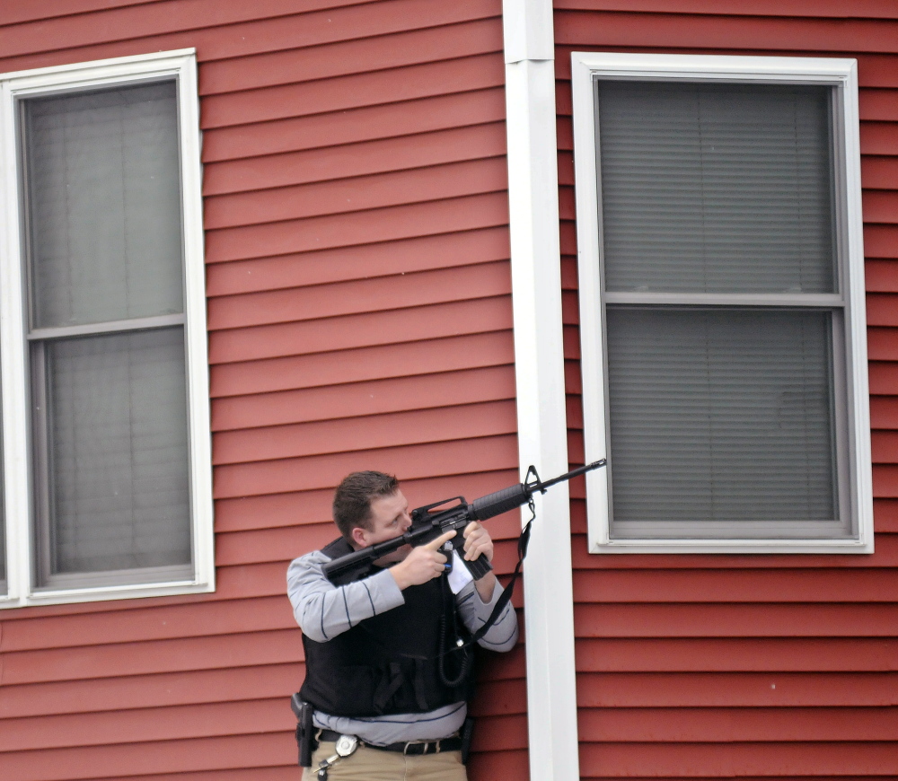 Augusta Police Detective Chris Blodgett aims a rifle Tuesday into a second floor apartment at 388 Water St. in Augusta as members of the department’s tactical team apprehend Lorne Sherwood.
