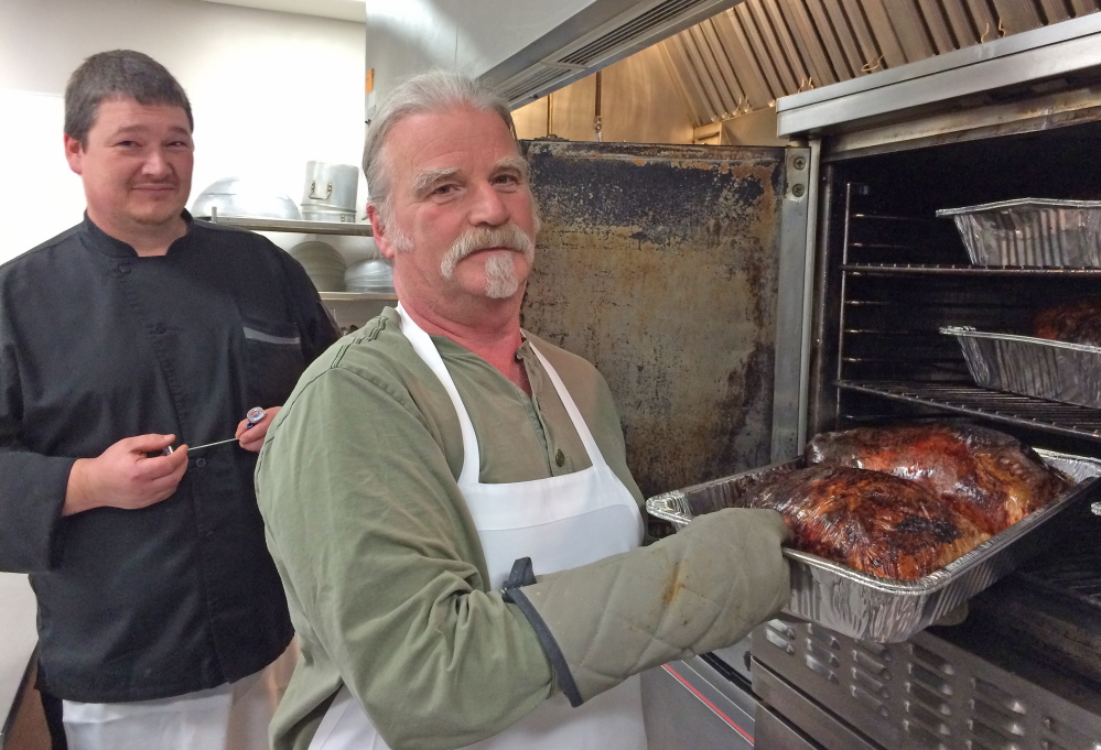 Fred Snyder, right, of Fairfield, and Rob Spencer, of Clinton, check the temperatures of turkeys at the Waterville Elks Lodge on Tuesday. The birds will be used to serve a free hot meal to close to 1,000 people on Christmas Day.