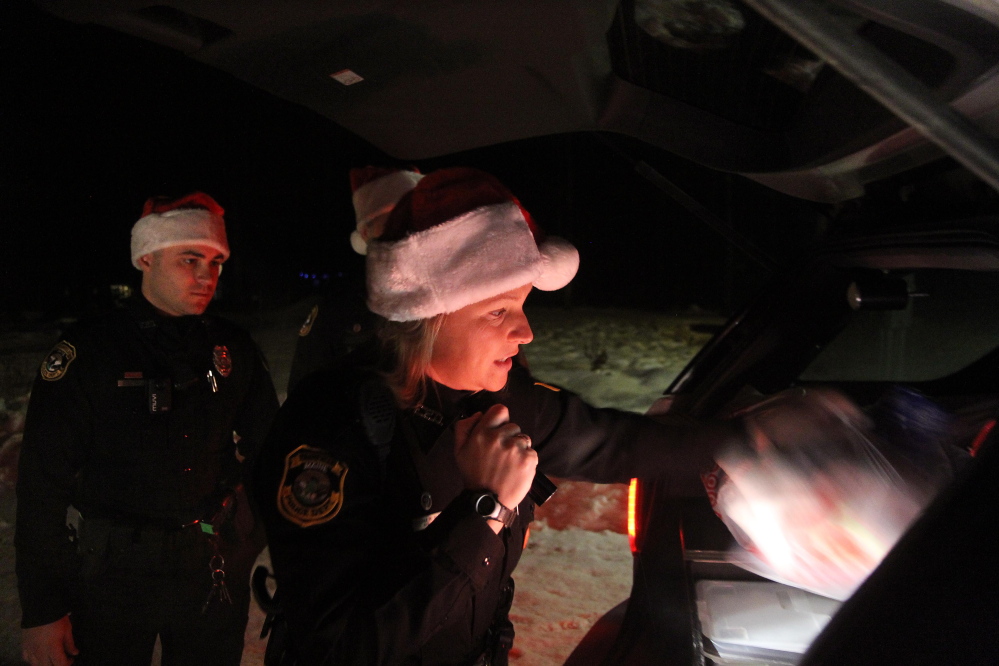 Fairfield police Officer Shanna Blodgett delivers Christmas presents on Tuesday night to local families on Martin Stream Road with fellow officers Jordan Brooks, left, and Patrick Mank.