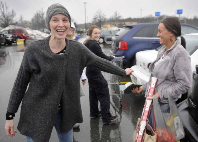 Karyn Sweeney, left, laughs after handing Sierra Warner, of Monmouth, a gift Wednesday in the parking lot of Walmart in Augusta.