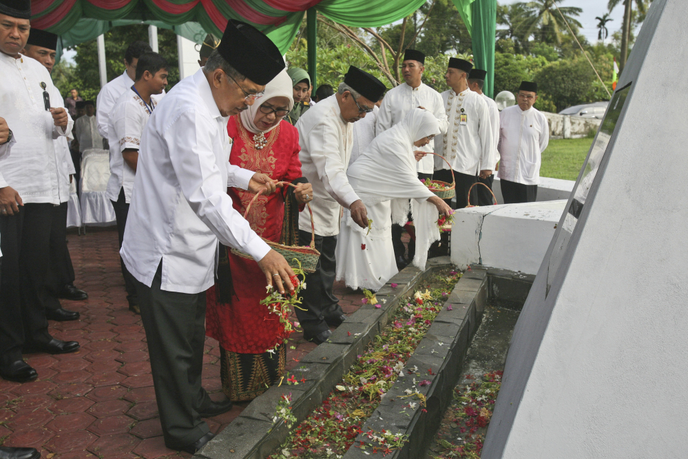 Indonesian Vice President Jusuf Kalla sprinkles flowers during a ceremony commemorating the 10th anniversary of the Indian Ocean tsunami at a mass grave in Aceh Besar, Aceh province, Indonesia, on Friday.