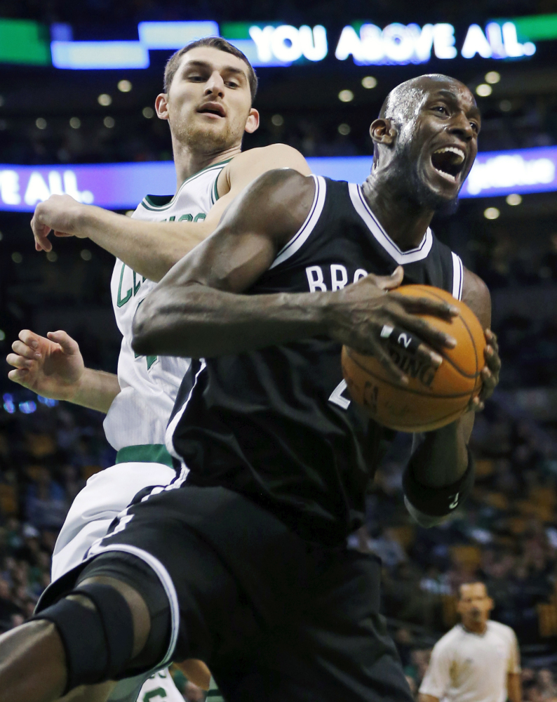 Brooklyn’s Kevin Garnett, right, grabs a rebound in front of Boston’s Tyler Zeller during the first quarter Friday in Boston.