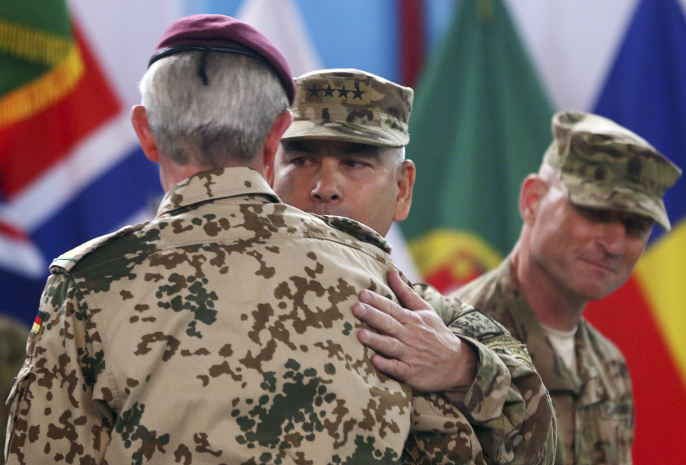 Commander of the International Security Assistance Force (ISAF), Gen. John Campbell, center, hugs ISAF Gen. Hans-Lothar Domrose, as Command Sgt. Maj. Delbert Byers watches them during a ceremony at the ISAF headquarters in Kabul, Afghanistan, on Sunday. The United States and NATO formally ended their war in Afghanistan on Sunday with the ceremony at their military headquarters in Kabul as the insurgency they fought for 13 years remains as ferocious and deadly as at any time since the 2001 invasion that unseated the Taliban regime following the Sept. 11 attacks.