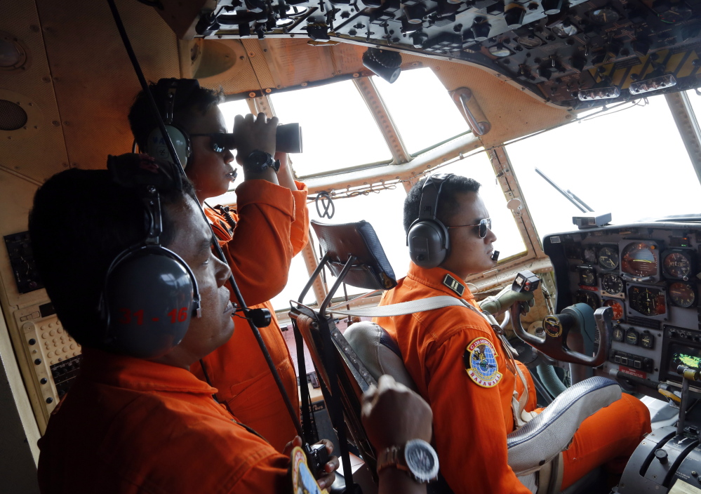 Crew members on an Indonesian Air Force plane search for debris from AirAsia Flight 8501 over Karimata Strait in Indonesia on Monday. The airliner vanished Sunday during stormy weather.