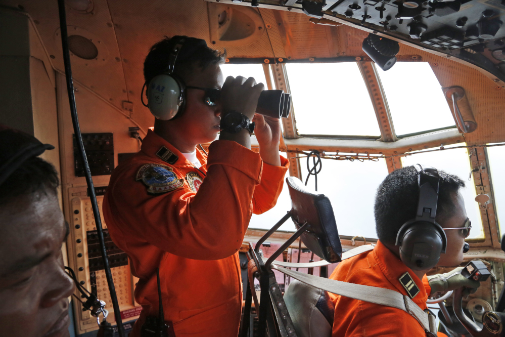 A crew of an Indonesian Air Force C-130 airplane of the 31st Air Squadron uses a binocular to scan the horizon during a search operation for the missing AirAsia flight 8501 jetliner over the waters of Karimata Strait in Indonesia, Monday. Search planes and ships from several countries on Monday were scouring Indonesian waters over which an AirAsia jet disappeared, more than a day into the region’s latest aviation mystery.
