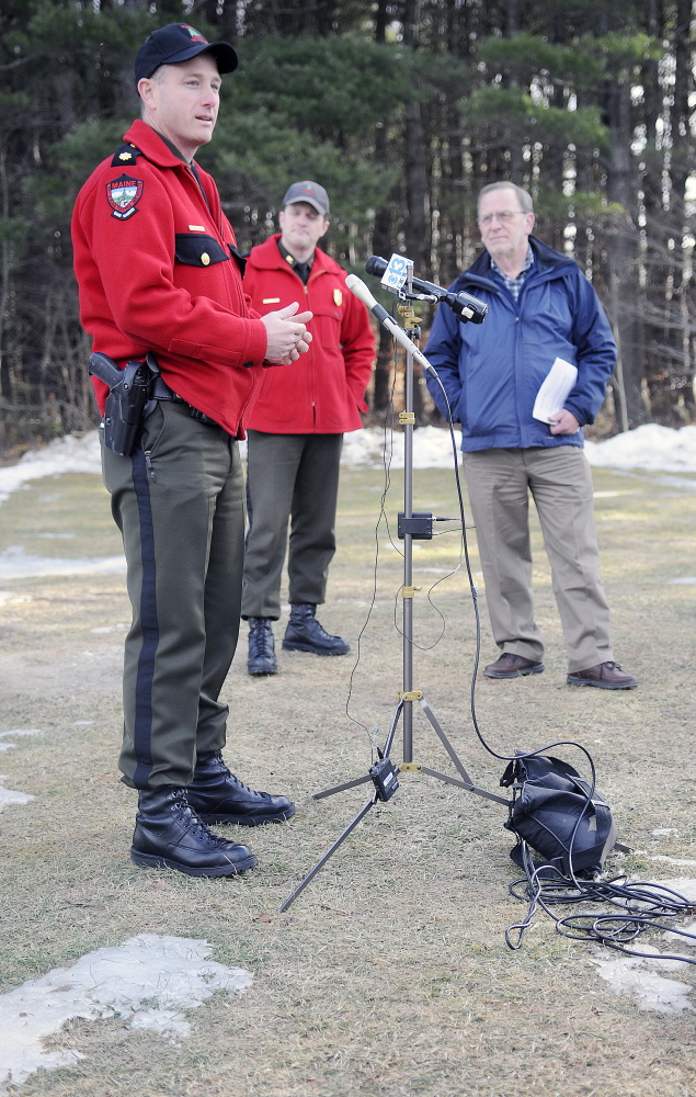 Standing on bare ground, Warden Service Maj. Chris Cloutier speaks Monday in Augusta about the need to ride snowmobiles safely this winter. At center is Warden Service Cpl. John MacDonald and Maine Snowmobile Association Executive Director Bob Meyers.