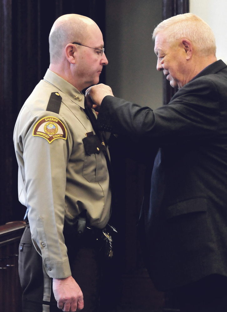 Retiring Somerset County Sheriff Barry DeLong, right, pins a sheriff’s badge on new Sheriff Dale Lancaster during a swearing-in ceremony at the Somerset Courthouse in Skowhegan Monday.