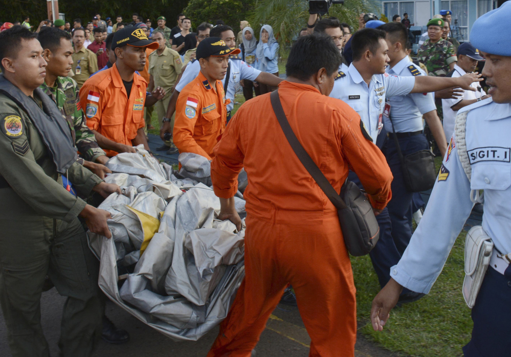 Indonesian Air Force personnel carry airplane parts recovered from the water near the site where AirAsia Flight 8501 disappeared, at the airbase in Pangkalan Bun, Central Borneo, Indonesia.