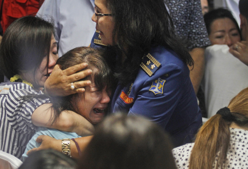 Relatives of passengers of AirAsia Flight 8501 react to news on television Tuesday about the discovery of bodies in the waters near where the jetliner disappeared.
The Associated Press