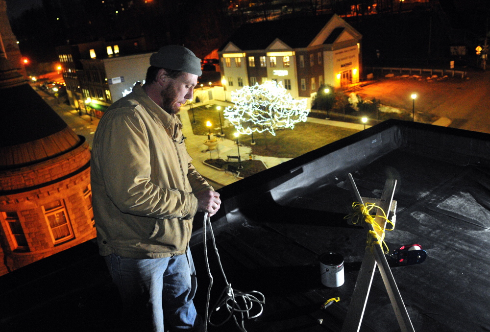Working on the roof setting up the ropes, Jason McFarland prepares to raise the New Year’s Eve ball on Tuesday at Gagliano’s Bistro on Water Street in Augusta.