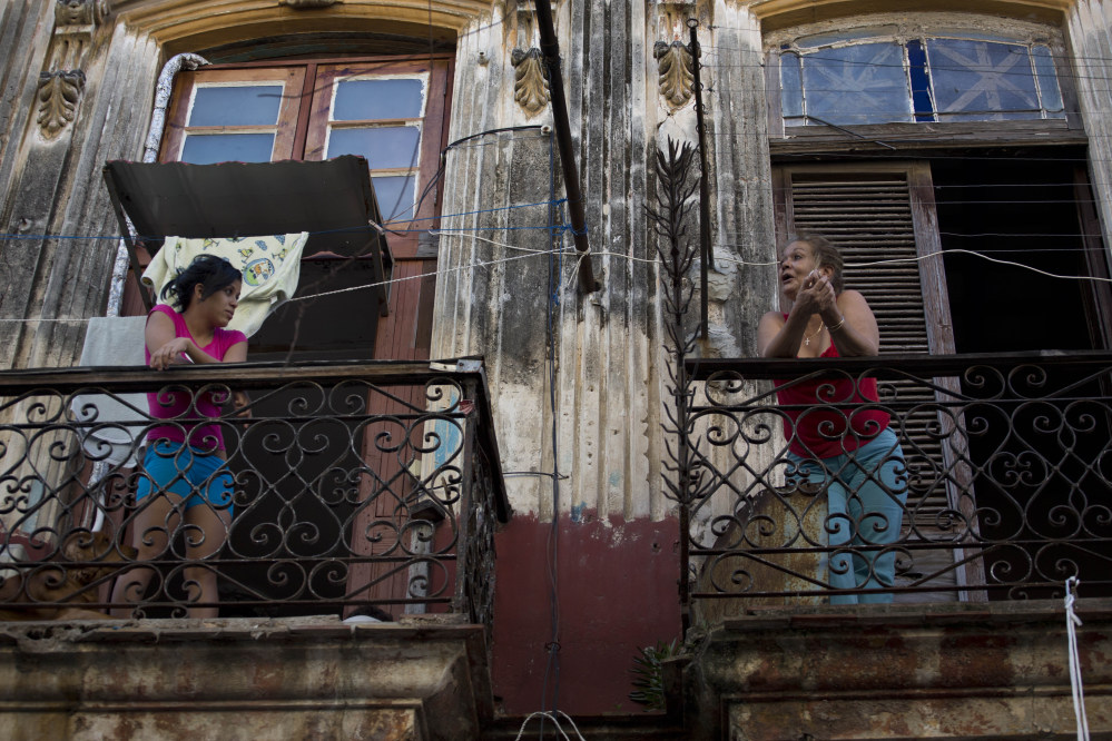 Two women talk across their balconies in Old Havana, Cuba, on Thursday. After a half-century of pointing fingers, a historic shift between the U.S. and Cuba could revitalize the flow of money and people between the two nations. The Associated Press