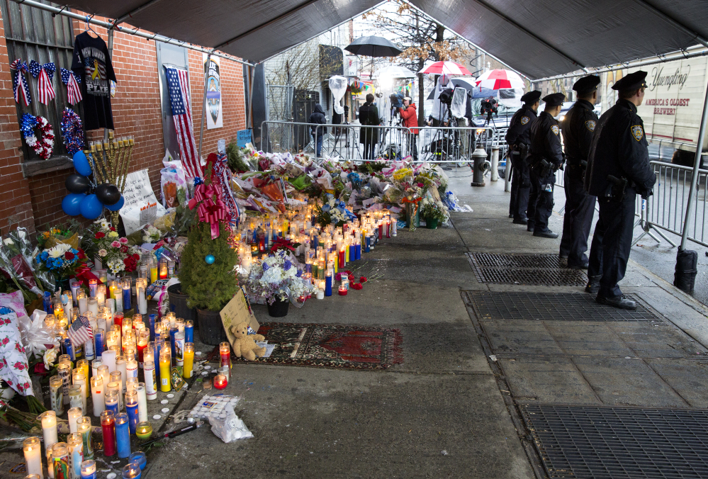 New York City police officers stand at a makeshift memorial Tuesday, near where two fellow police officers, Rafael Ramos and Wenjian Liu, were shot and killed in an apparent ambush in the Brooklyn borough of New York. The Associated Press