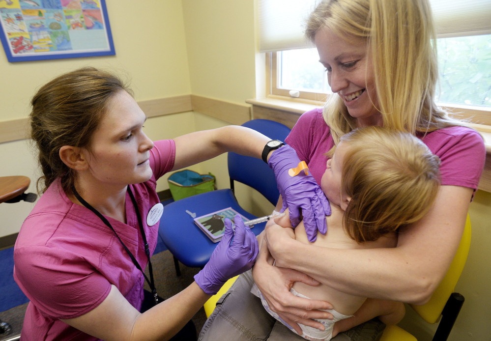 Amber Dugan of Durham holds Tessa as she gets a vaccination from Grace Montgomery at InterMed in Yarmouth. A new bill calls for parents who want to opt out of child immunizations for philosophic reasons to first consult with a primary care professional. Shawn Patrick Ouellette/2014 Press Herald file