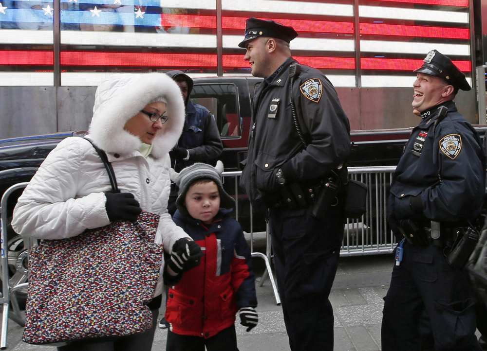 A woman and a child make their way through Times Square as New York City police officers share a laugh while patrolling the streets on Tuesday. 