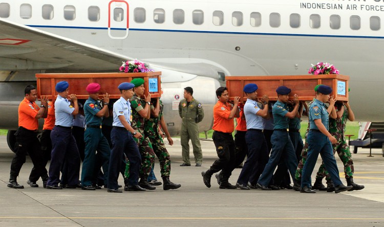 Indonesian soldiers carry coffins containing bodies of victims of AirAsia Flight 8501 upon arrival at  Indonesian Military Air Force base in Surabaya, Indonesia, Wednesday. A massive hunt for the victims of the jet resumed in the Java Sea on Wednesday, but wind, strong currents and high surf hampered recovery efforts as distraught family members anxiously waited to identify their loved ones. The Associated Press