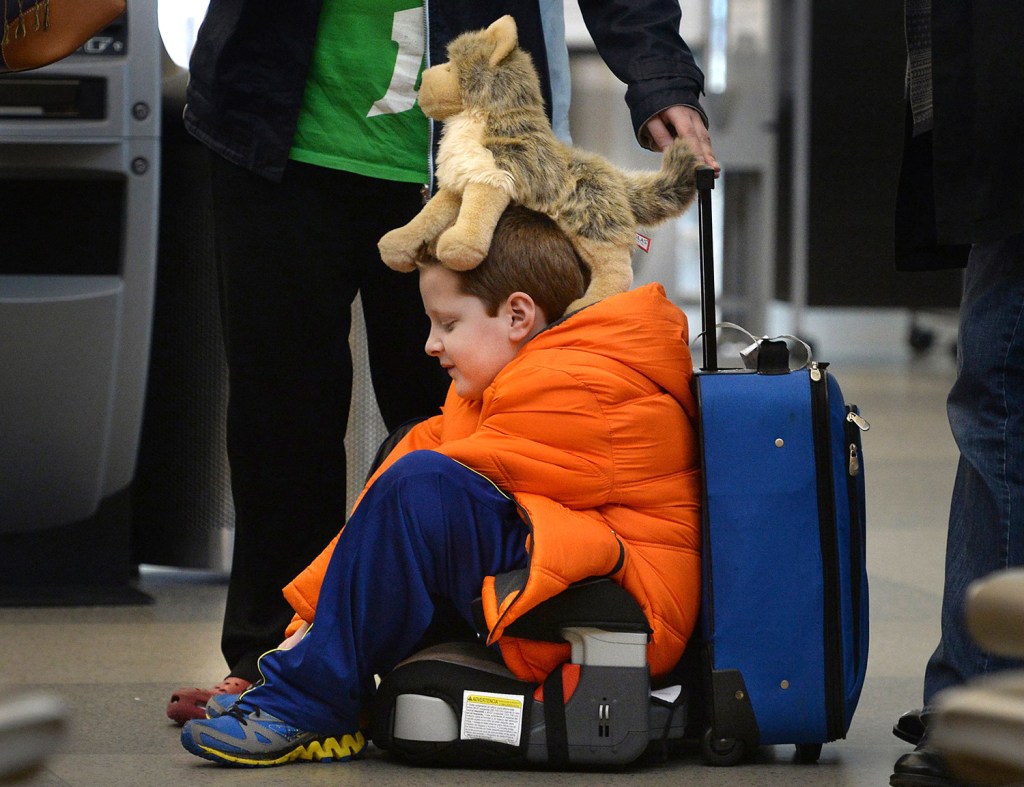 David Welborn, 7, sits in the lost luggage line at the Delta Airlines desk at RDU International Airport on Tuesday  With his trusty dog "Wolfbaby" perched on his head, he was with his mother and about 15 other people trying to find their bags after a cross country flight from Washington State. The Associated Press