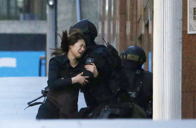 A hostage runs towards a police officer outside Lindt cafe, where other hostages are being held, in Martin Place in central Sydney Monday.  