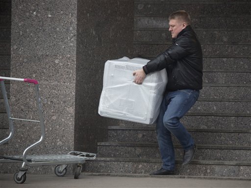 A man carries a dishwasher he purchased in St.Petersburg, Russia, Wednesday. The collapse of the national currency triggered a spending spree by Russians desperate to buy cars and home appliances before prices shoot higher. The Associated Press