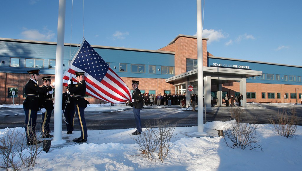 A military honor guard raises a flag Monday outside the new offices of the Department of Health and Human Services and Department of Labor in South Portland . The new building also houses regional offices of the Department of Veterans' Affairs. Gregory Rec/Staff Photographer