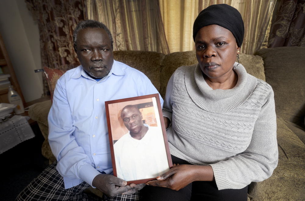 Sitting in the family’s home in Portland on Dec. 9, Robert Lobor and Christina Marring hold an April 2014 photograph of their son, Richard Lobor, who was shot to death in Portland recently. Like many refugees, Lobor was exposed to trauma as a child.