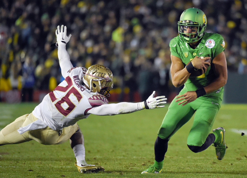 Oregon quarterback Marcus Mariota, right, scores past Florida State defensive back P.J. Williams during the second half of the Rose Bowl on Thursday in Pasadena, Calif. Oregon will meet Ohio State in the national championship game on Jan. 12.