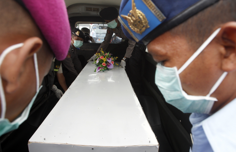 Indonesian military personnel load a coffin containing the body of a victim of AirAsia Flight 8501 onto an ambulance upon arrival at Juanda Naval Airbase in Surabaya, East Java, Indonesia.