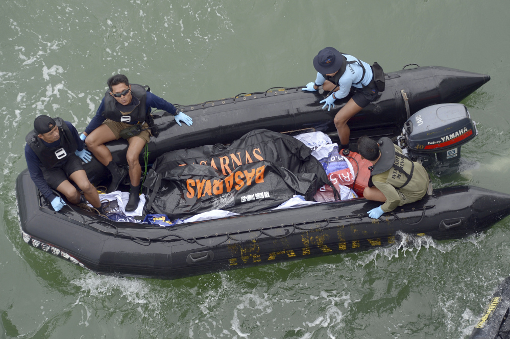 Indonesian Navy personnel carry a plastic bag containing the dead body of a passenger of AirAsia Flight 8501 at sea off the coast of Pangkalan Bun, Indonesia.