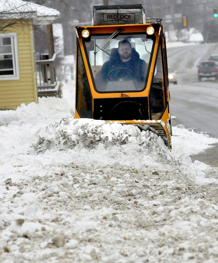 Waterville Public Works employee Kirk Lachance clears sidewalks of the snow that fell on Sunday.
