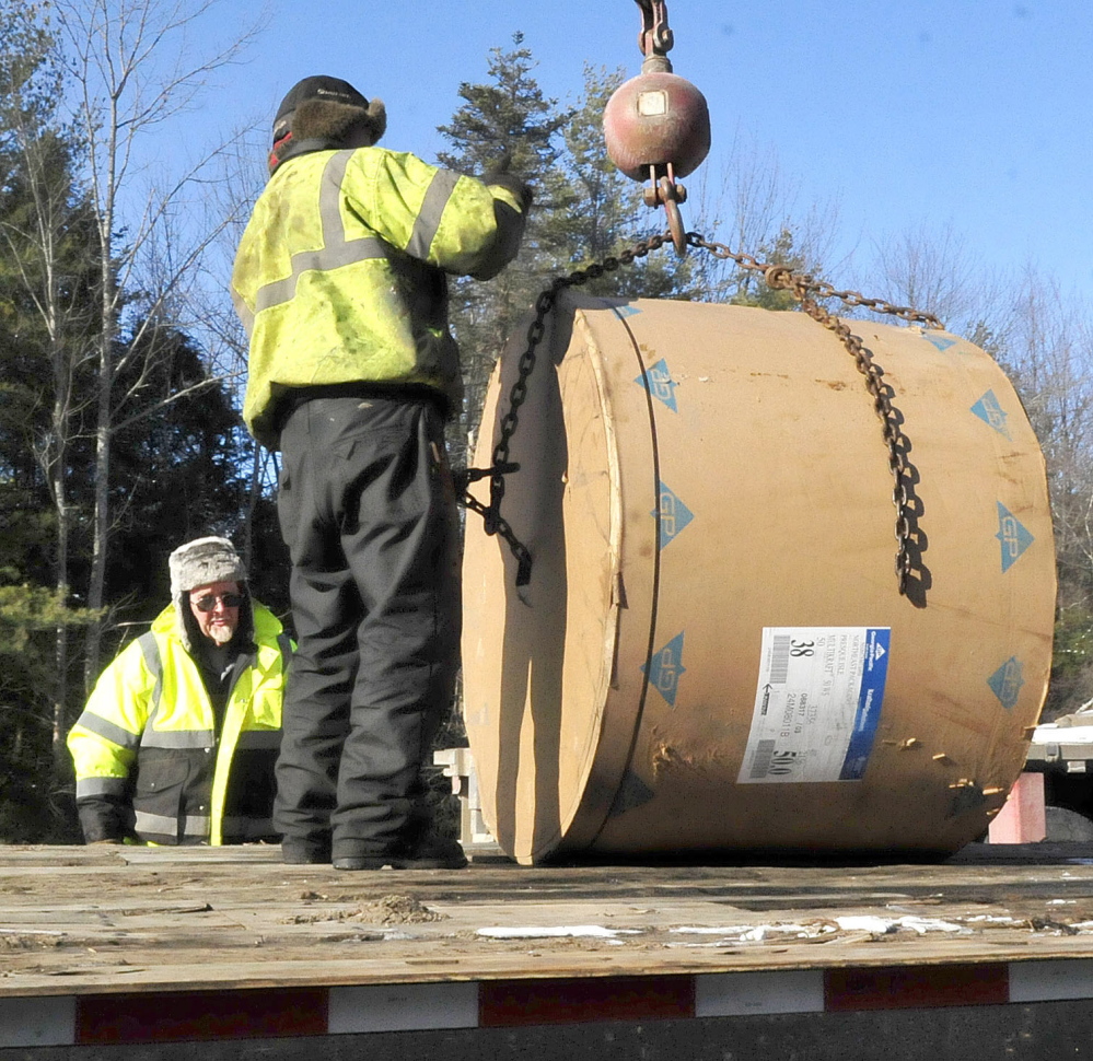 Workers on Monday load rolls of paper after using a crane to unload a tractor-trailer that slid and overturned on the northbound lane of I-95 in Sidney earlier Monday. Traffic was detoured from exit 113 to exit 120.
