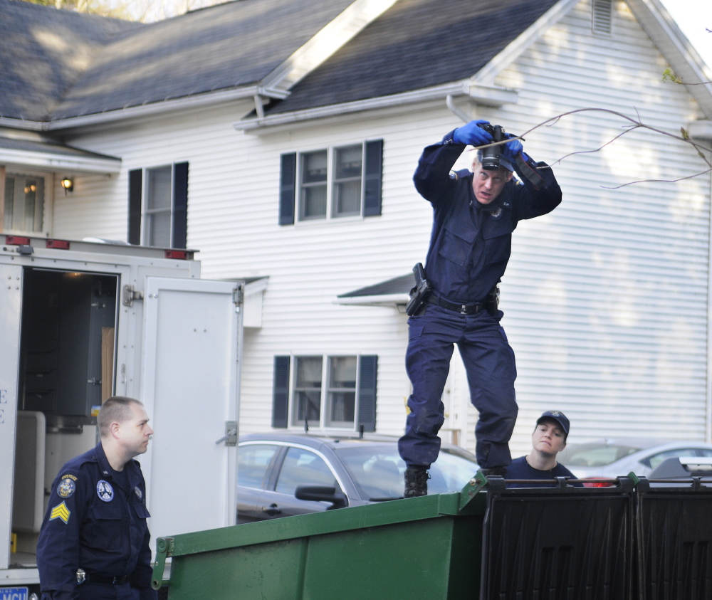 State Police Detective Terry James, center, photographs the interior of a Dumpster May 5, 2014, outside the apartment that Leroy Smith Jr. shared with his son in South Gardiner. Detective Sgt. Jason Richards, left, and Trooper Breanne Petrini searched the Dumpster in the evening after the elder Smith’s body was recovered in Richmond.