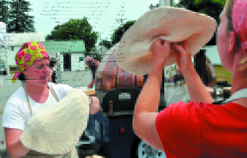 Amber Lambke, left, director of the Maine Grain Alliance, and Katherine Creswell, right, hand toss pizza dough at the Maine Grain Alliance pizza tent at the Artisan Bread Fair at the Skowhegan State Fairgrounds.