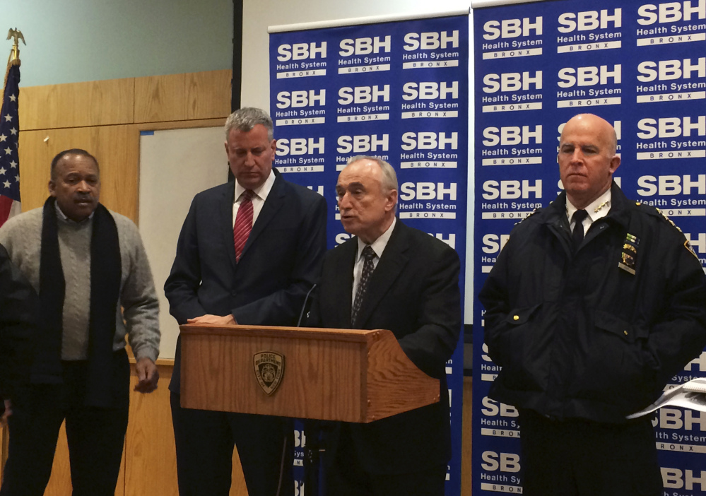 New York City Mayor Bill de Blasio, second left, stands by as New York Police Department Commissioner William Bratton, second right, speaks at a news conference at St. Barnabas Hospital in the Bronx section of New York, early Tuesday, after two New York City police officers were shot late Monday night.