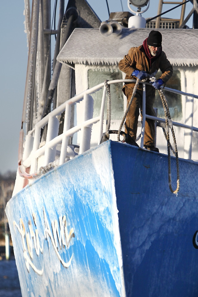 Jorge Furtado, first mate of the Lori Ann, prepares to tie the frozen clam ship to the dock in Fairhaven, Mass., on Thursday after arriving from a sea voyage, as frigid temperatures blanket the area.