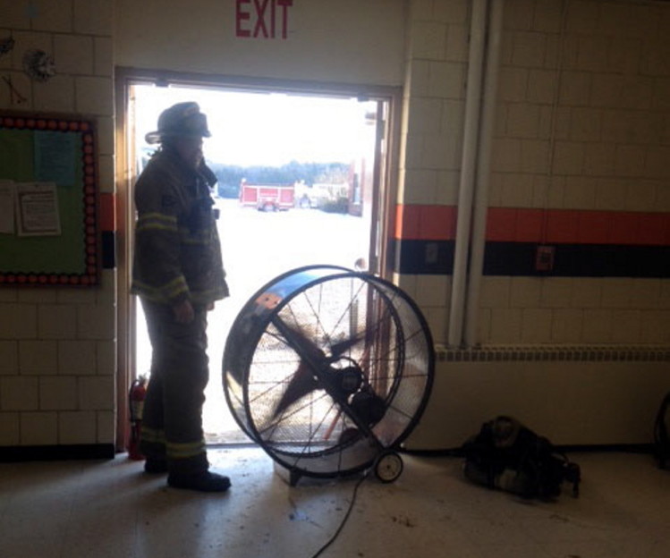 Skowhegan fire Lt. Matthew Quinn sets up a fan to clear smoke from Skowhegan Area High School after a bathroom fire Friday afternoon