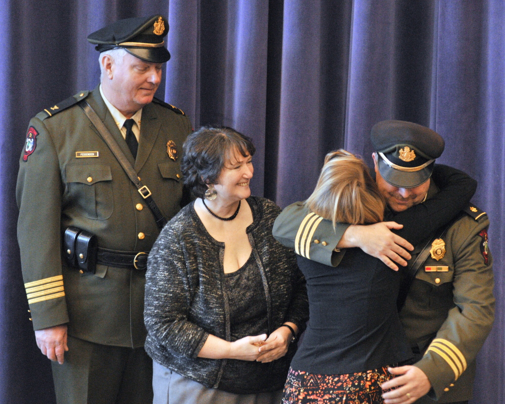 New Marine Patrol Col. Jon Cornish, right, hugs his daughter Katrina Cornish after she pinned his badge on him during a change of command ceremony on Friday at the Maine Criminal Justice Academy in Vassalboro. Retiring Marine Patrol Col. Joe Fessenden, left, and Cornish’s wife, Kim Cornish, also attended the ceremony.