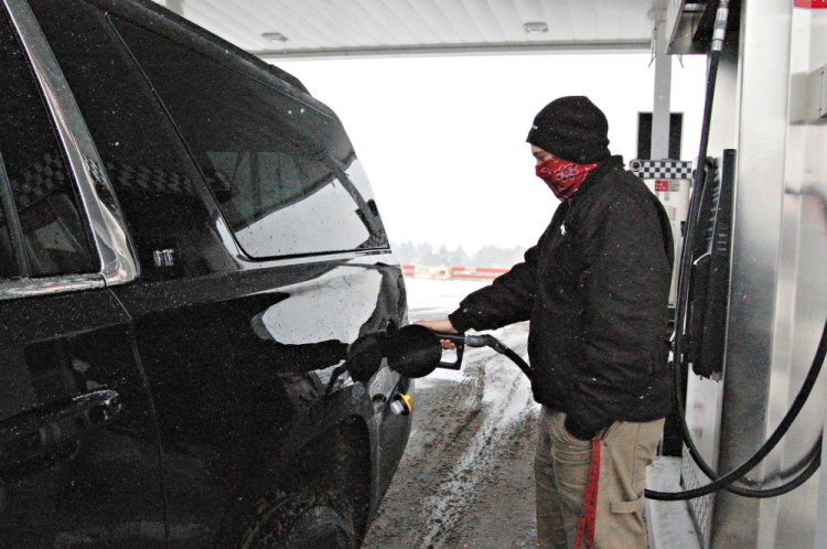 Zackary Grote, a business major at Thomas College in Waterville, attempts to stay warm while fueling up Friday at J&S Express Stop on Kennedy Memorial Drive in Waterville.