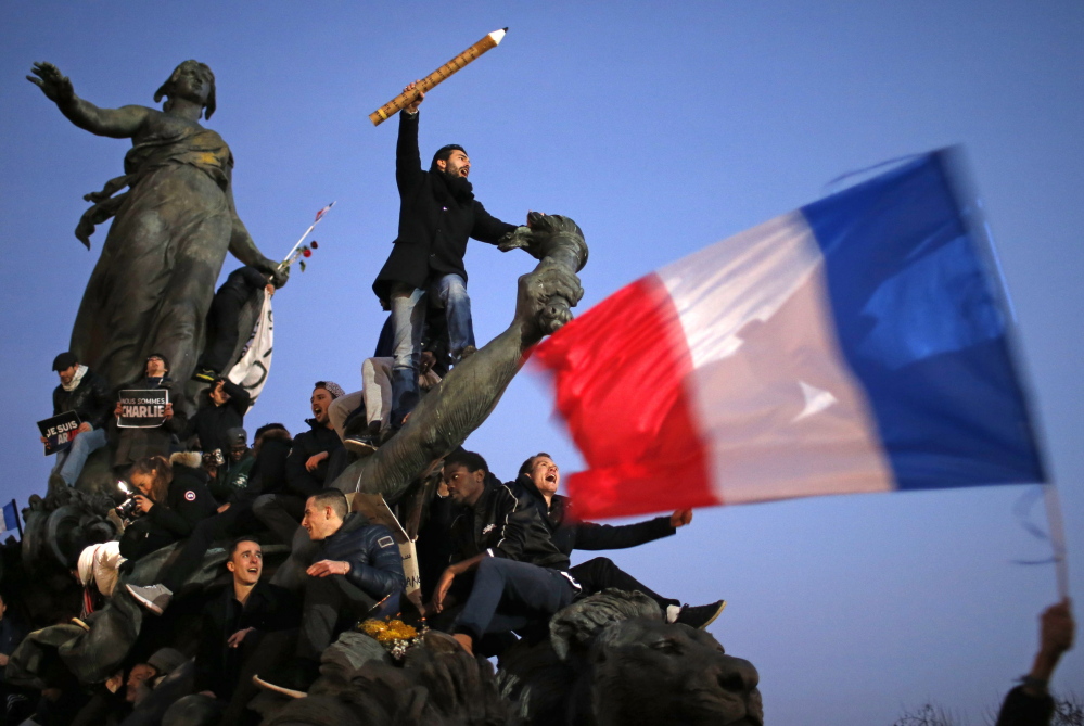 Some marchers carried France’s flag and others held giant pens or pencils in a tribute to the cartoonists killed in the attack on the satirical French newspaper Charlie Hebdo.