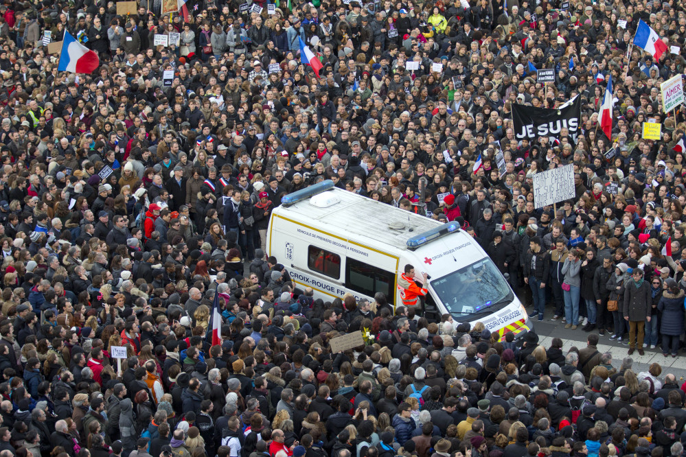 An ambulance makes its way as thousands of people gather at Republique square in Paris, France, Sunday, Jan. 11, 2015.  Thousands of people began filling France’s iconic Republique plaza, and world leaders converged on Paris in a rally of defiance and sorrow on Sunday to honor the 17 victims of three days of bloodshed that left France on alert for more violence. (AP Photo/Peter Dejong)