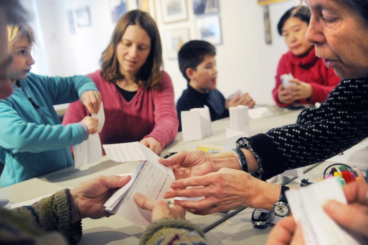 Margo Ogden, right, demonstrates how to fold paper into books during a bookmaking class at Harlow Gallery in Hallowell on Sunday