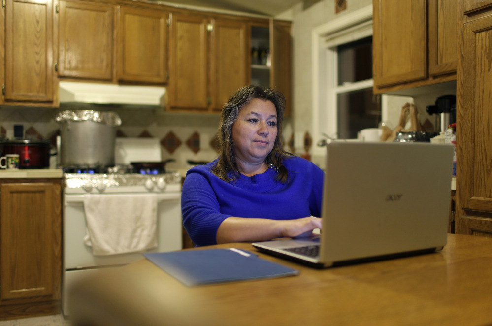 In this Dec. 2, 2014 photo, Loly Garcia works on a computer at her home in El Jebel, Colo., a small community about 20 miles northwest of Aspen, Colo. Garcia has taken lower-paying jobs in order to work closer to home.