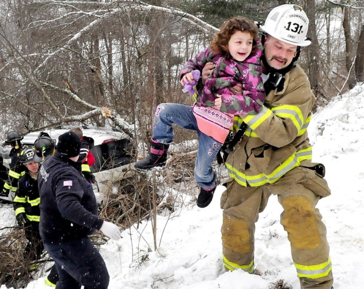Skowhegan Fire Chief Shawn Howard  carries a young girl who survived the crash when the vehicle in which she and three other children and an adult driver were riding slid off Norridgewock Road in Skowhegan and went down a ravine and struck a tree in January 2015.  The photo won first place for a spot news photo in the Maine Press Association's 2015 contest.