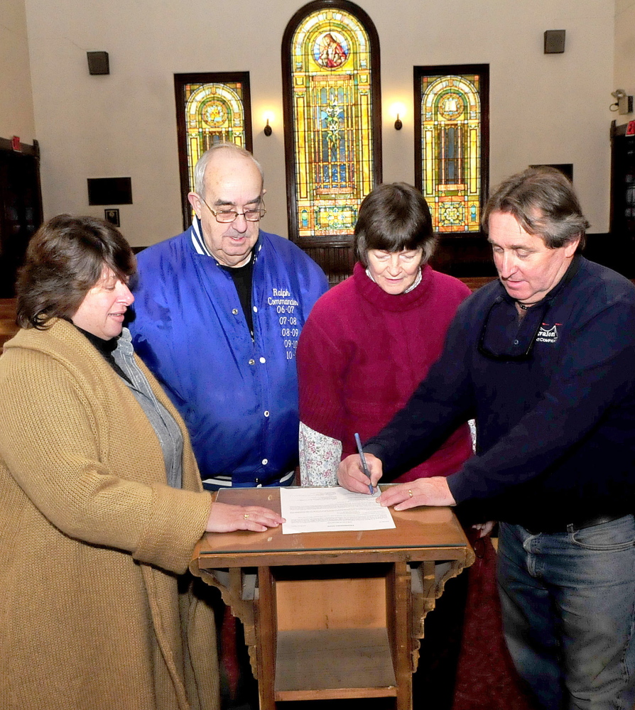 Tom O’Brien, right, signs a deed for the Madison Congregational Church in Madison on Monday. Looking on is his wife Stacy, left, and church members Ralph Withee and Elizabeth Coro. The O’Briens plan to turn the church into a wedding and event venue called the Somerset Abbey.